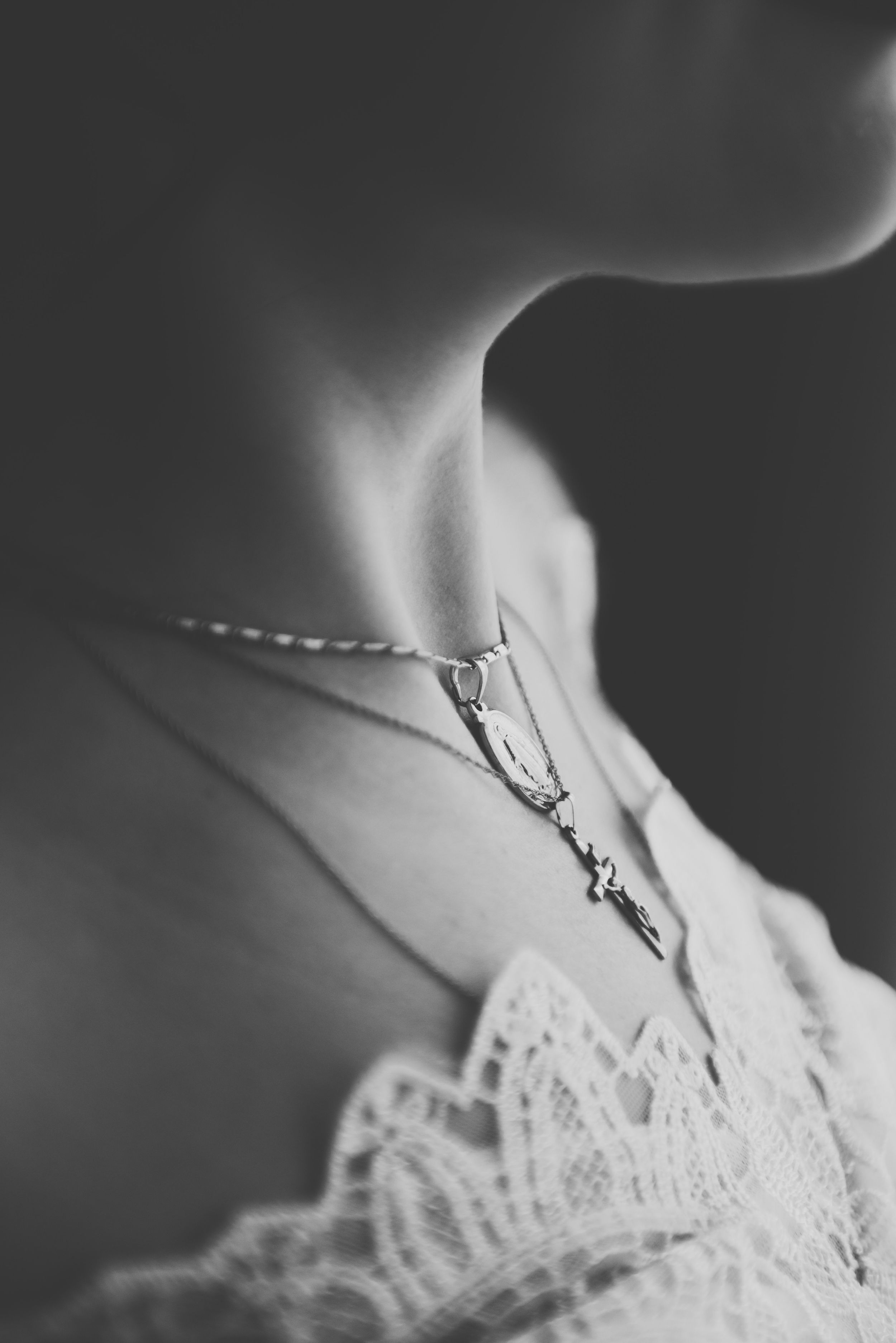 Delicate lace and necklace detail in black and white closeup macro photography.