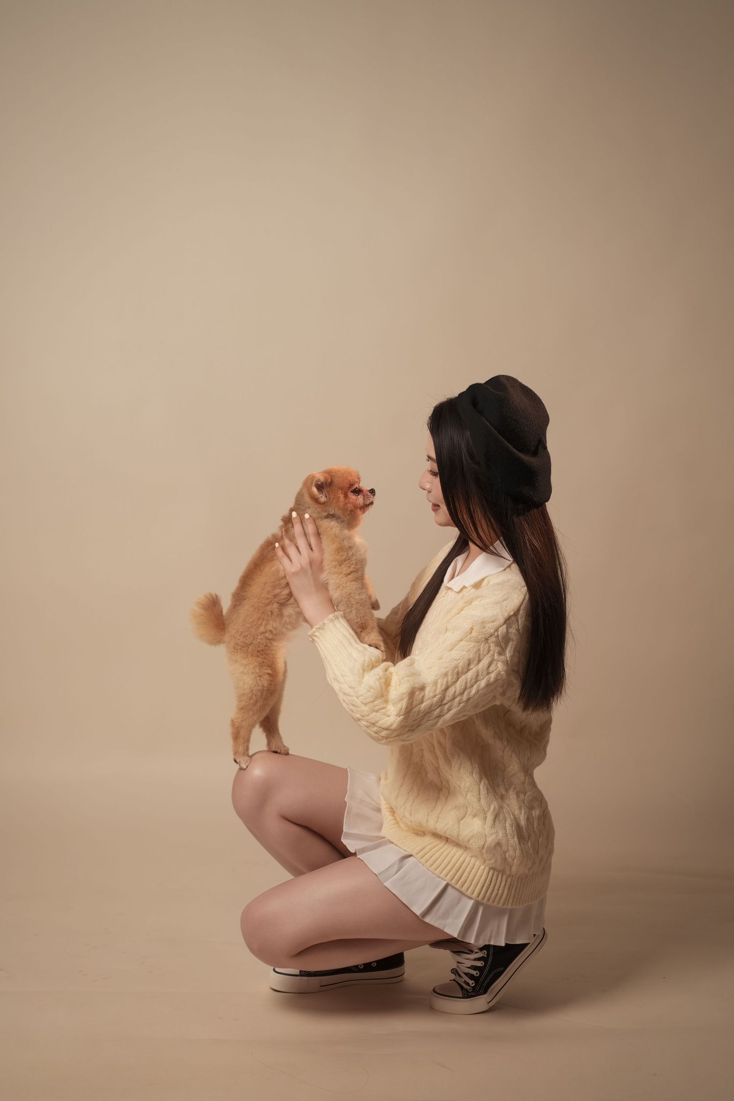 A series of casual poses featuring a person in a cream sweater playing with a small fluffy Pomeranian dog.
