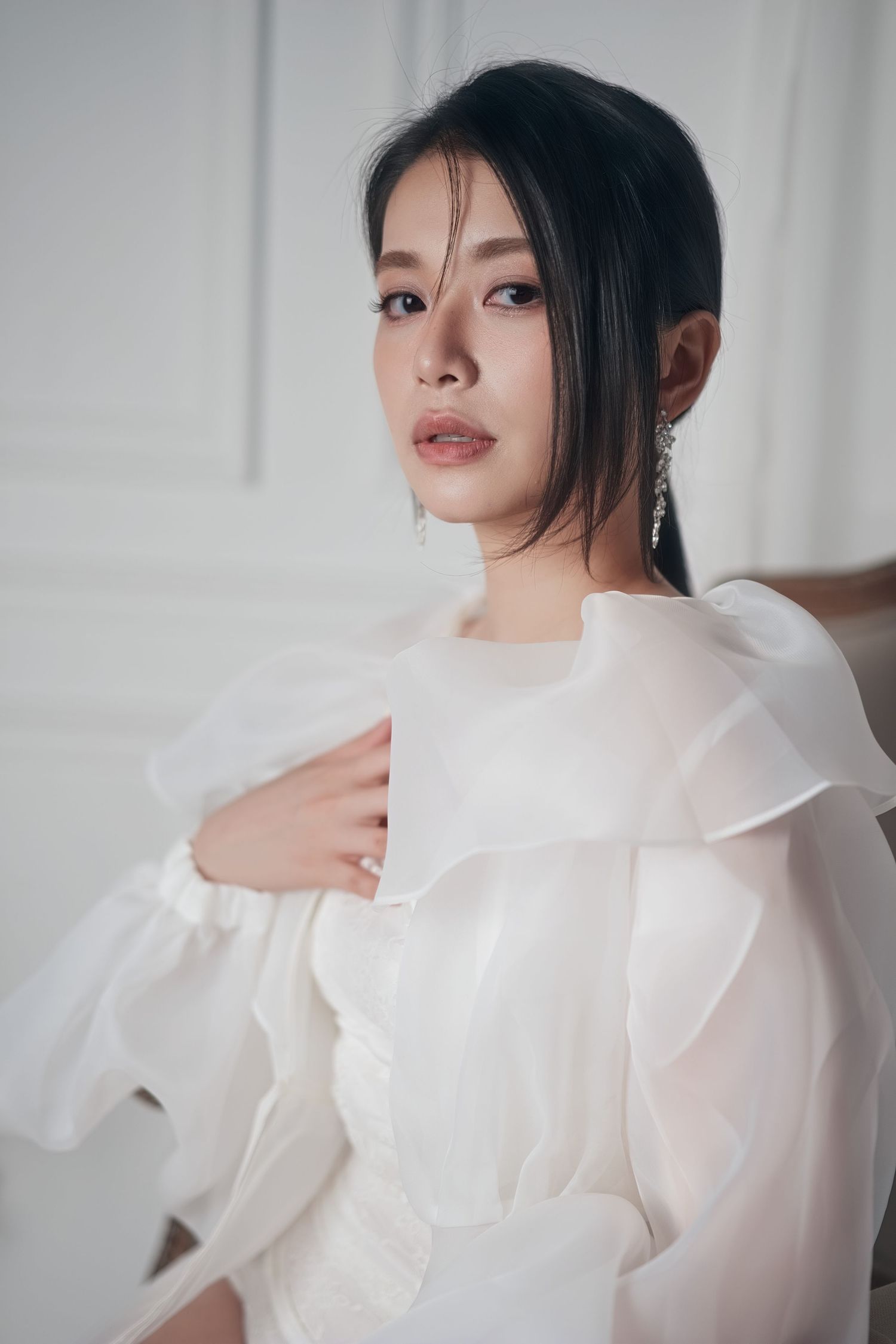 A series of ethereal portraits featuring a subject in a flowing white ruffled blouse against a light backdrop.