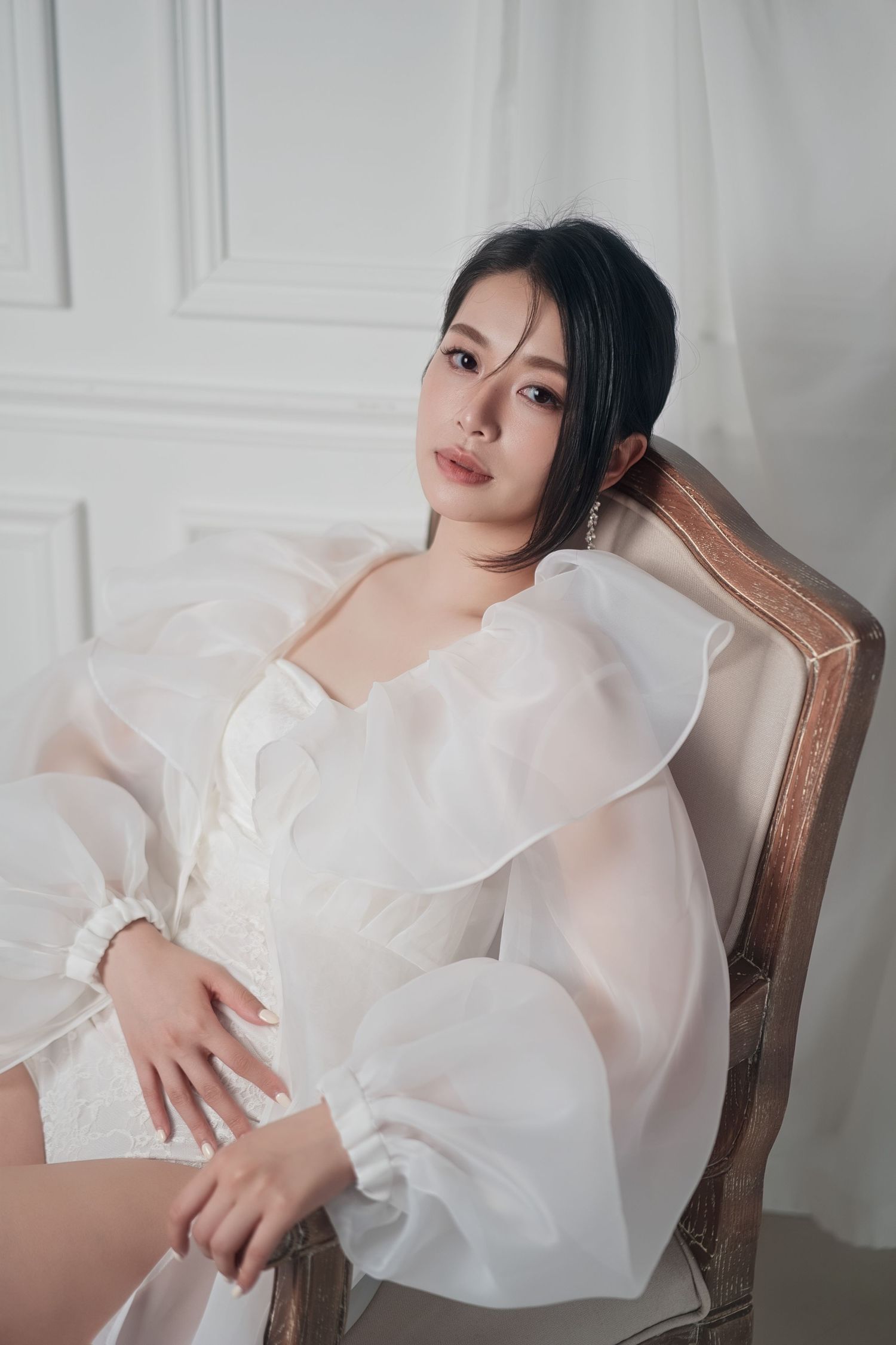 Artistic portrait series showing a person in a flowing white ruffled top posing elegantly on a vintage chair.