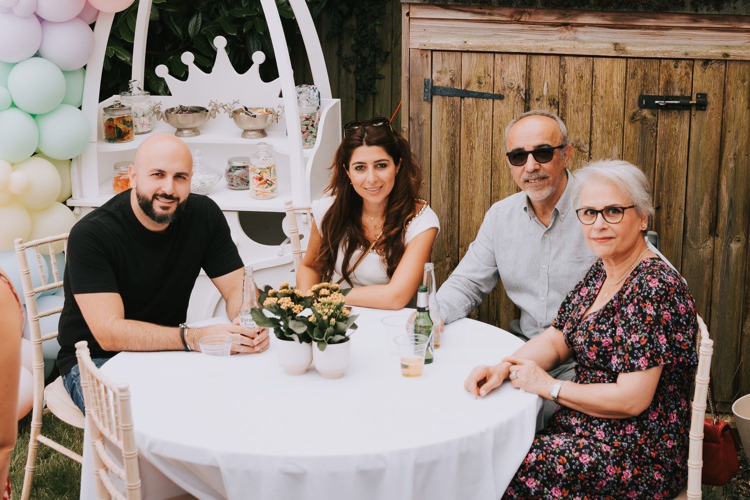 4 guests at a birthday party sat on a round table posed and smiling