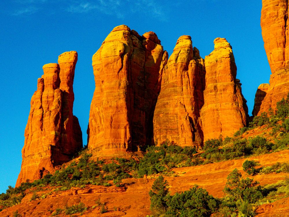 Majestic red sandstone buttes stand tall against vibrant blue sky in Sedona Arizona.