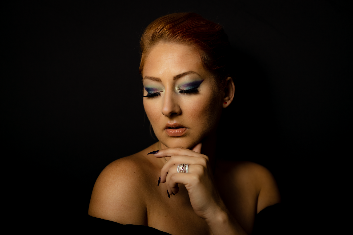 Dramatic beauty portrait with sophisticated makeup against dark background.