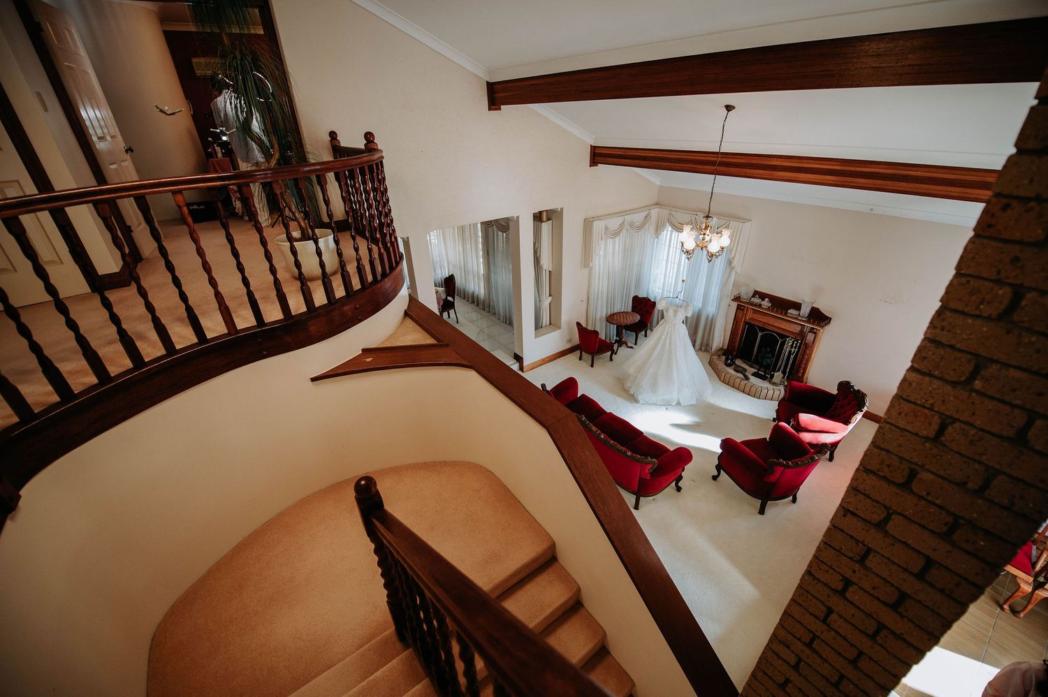 Interior view of elegant spiral staircase with hanging wedding dress in foreground.
