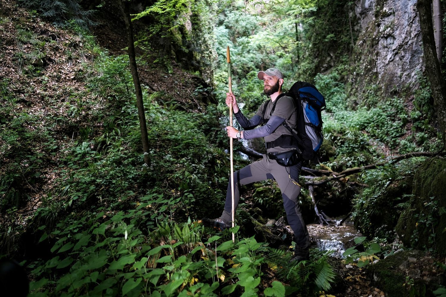 Pohodnik z nahrbtnikom hodi ob potoku skozi gozd in raziskuje naravo Foto Colarič