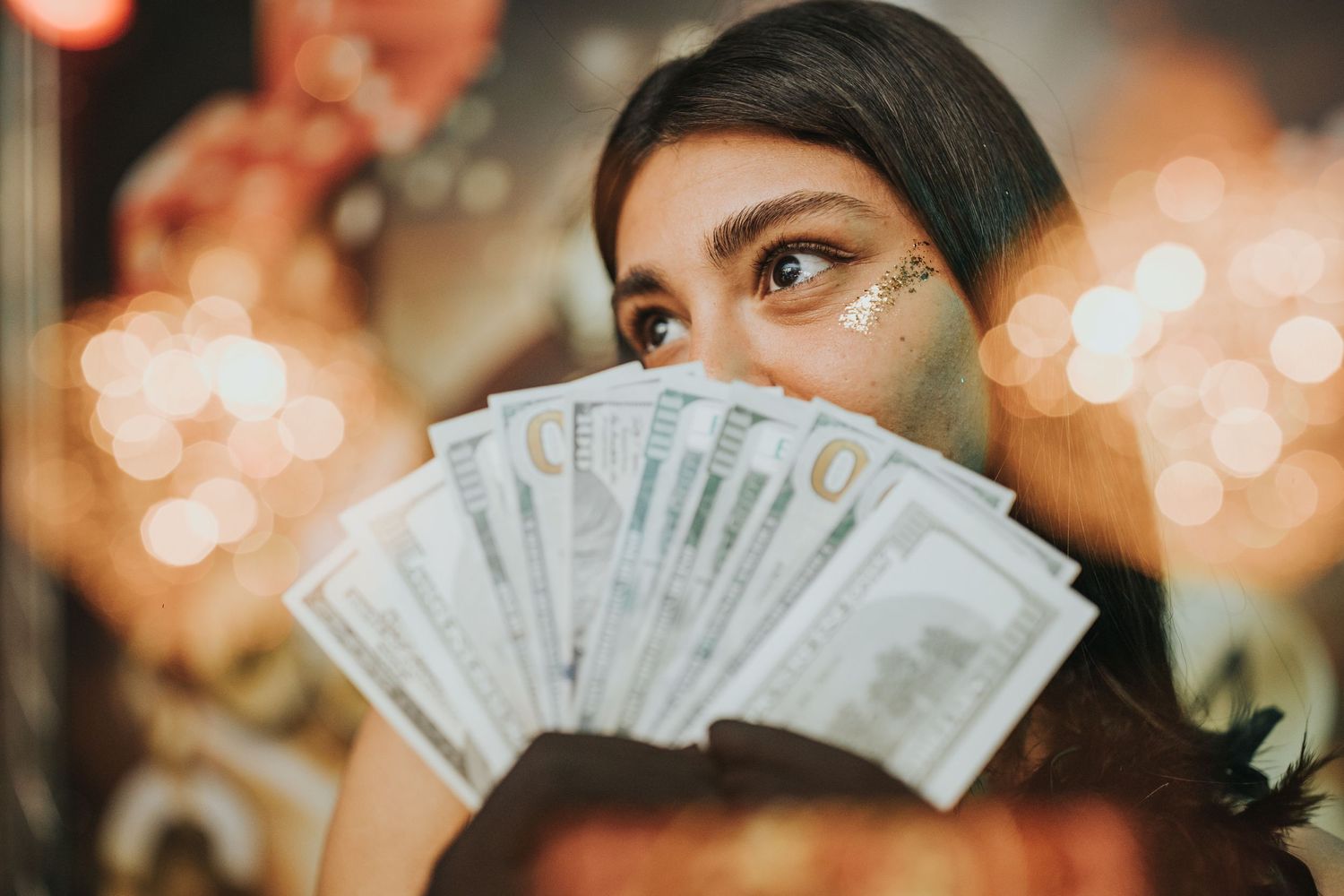 Displaying fanned cash money against bokeh lights background.