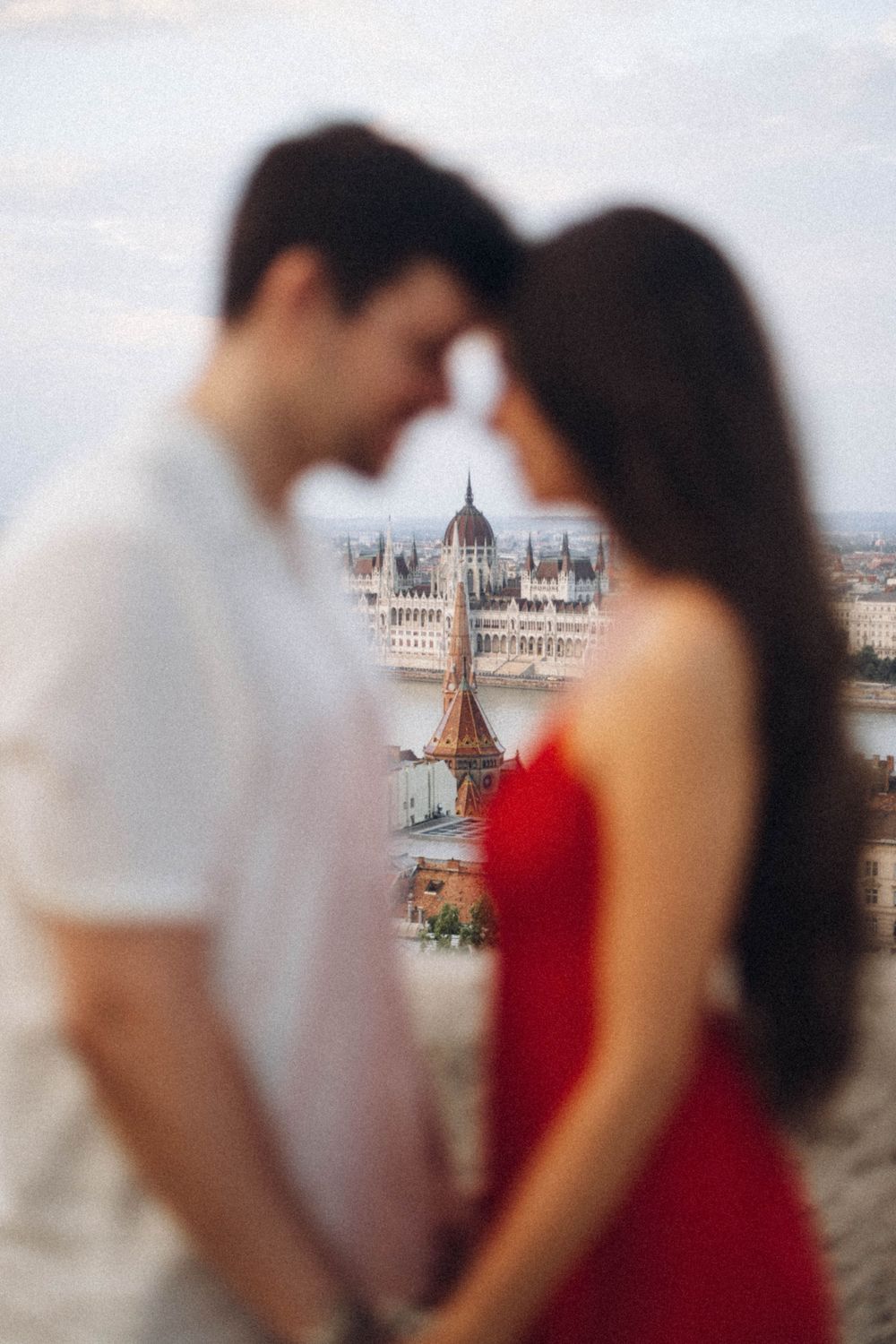 A couple shares an intimate moment with the stunning Budapest Parliament building in sharp focus behind them.