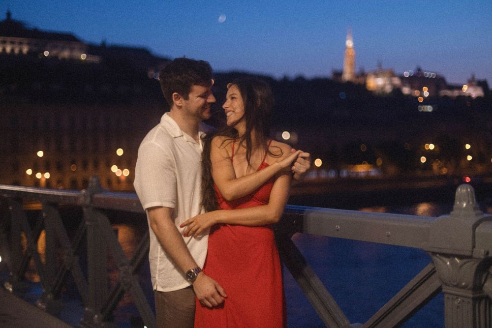 Romantic couple gazing at each other on a bridge at night in Budapest, Hungary.