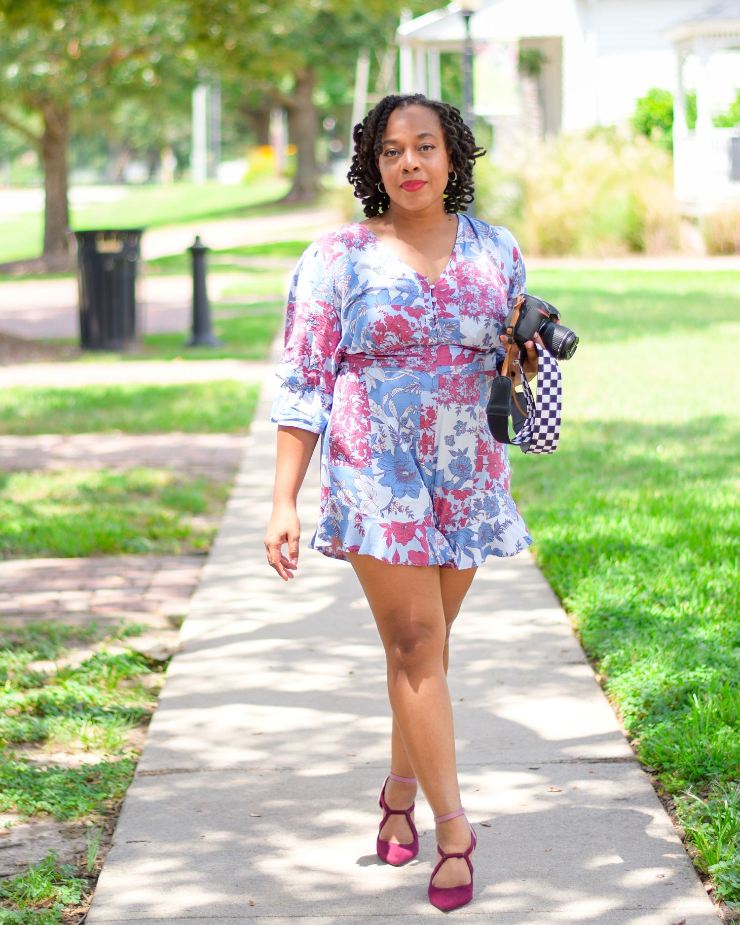 Lifestyle photos of floral romper outfit styled with pink heels on garden path.