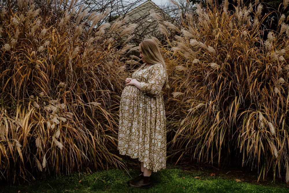 Pregnant lady standing surrounded by toi tois in a garden in Christchurch, New Zealand