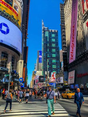 Bustling Times Square intersection with modern skyscrapers, digital billboards, and yellow taxis in New York City.