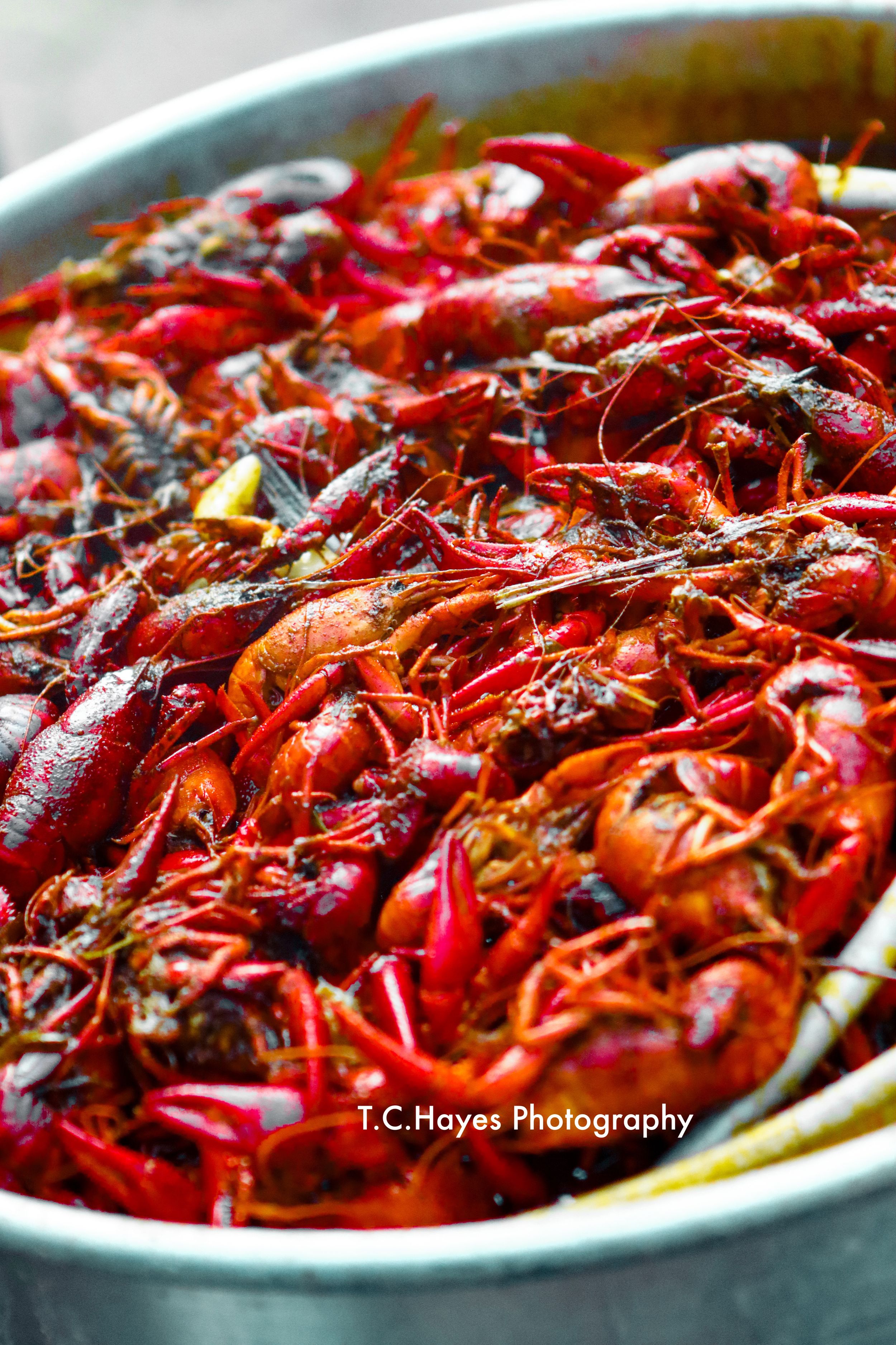 Large pot of bright red boiled crawfish with seasoning photographed from above.