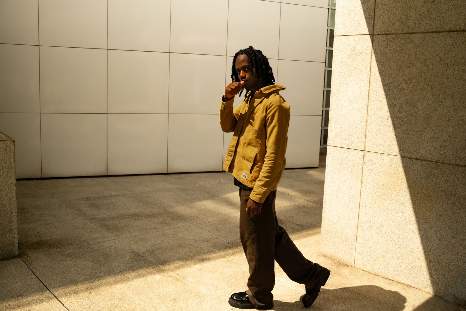 Person in yellow jacket walking through modern architectural space with dramatic lighting.