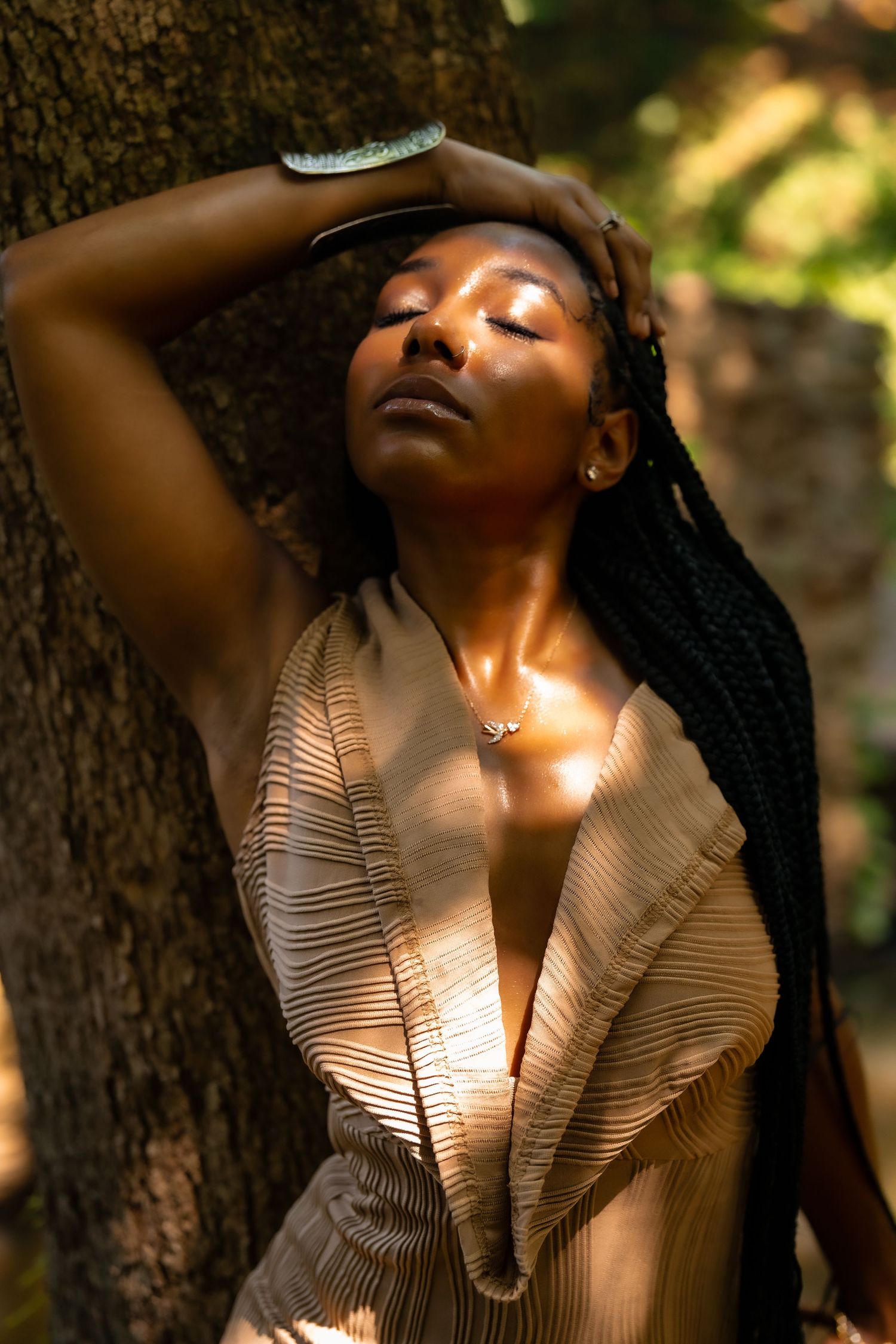 Sunlit portrait through forest canopy creating dappled lighting effects on beige clothing.