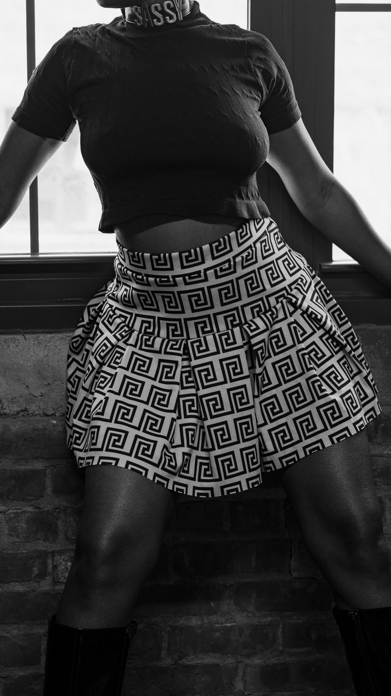 Black and white photo showcasing a flared skirt with geometric Greek key pattern and fitted black top.
