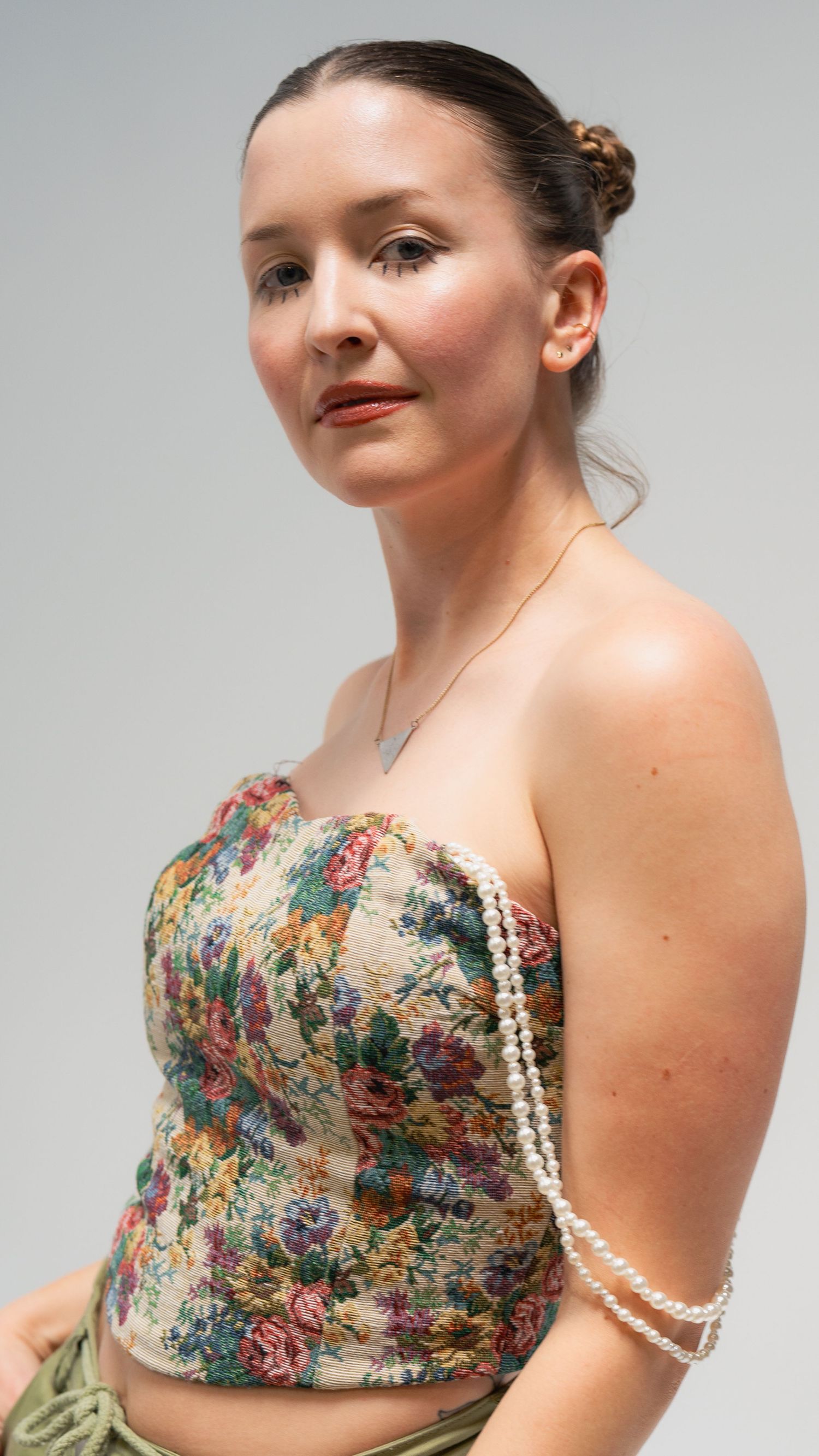 Studio portrait featuring floral corset top with delicate pearl accessories.