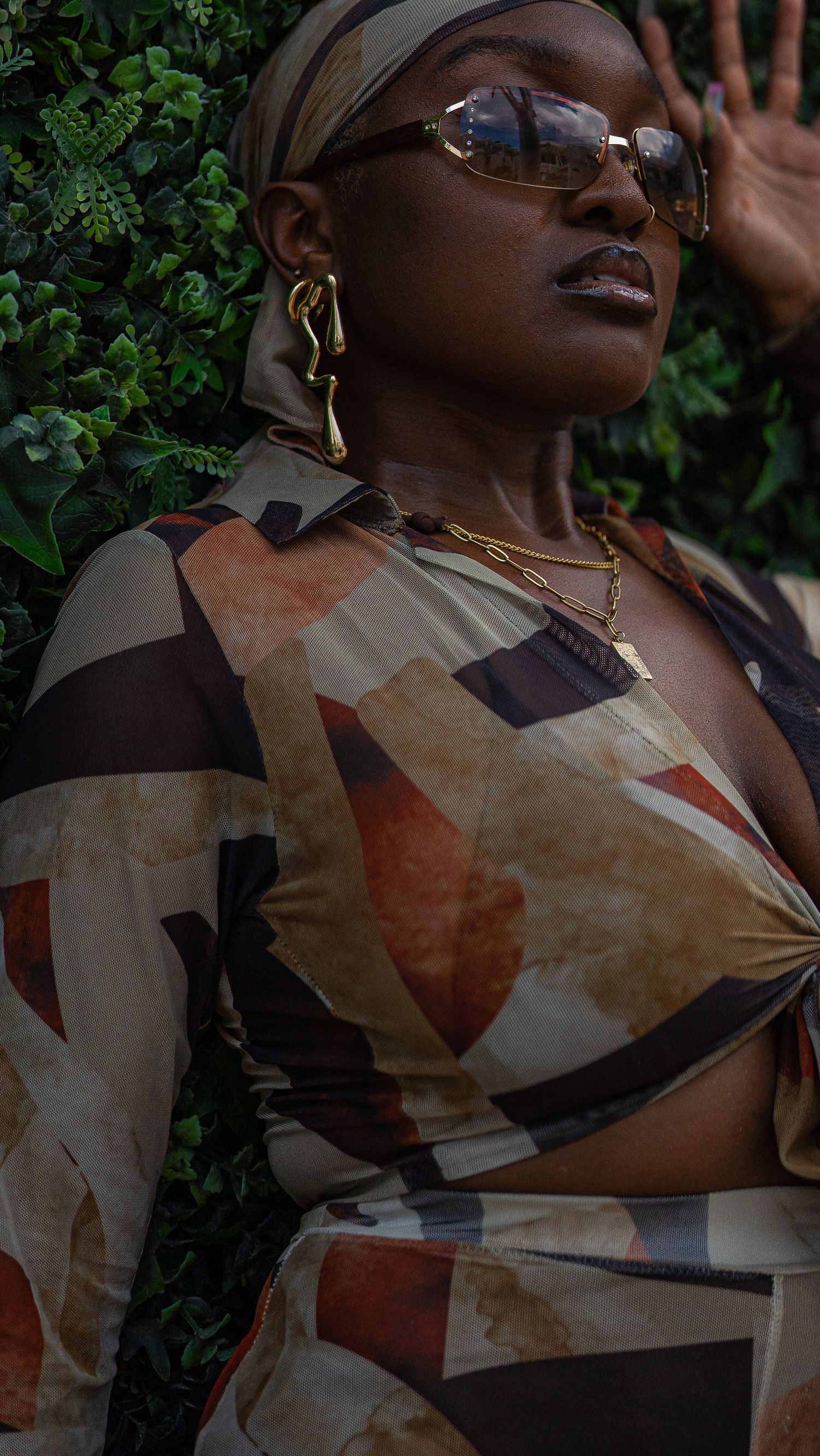 Fashion portrait in earth-toned geometric print outfit with statement sunglasses.