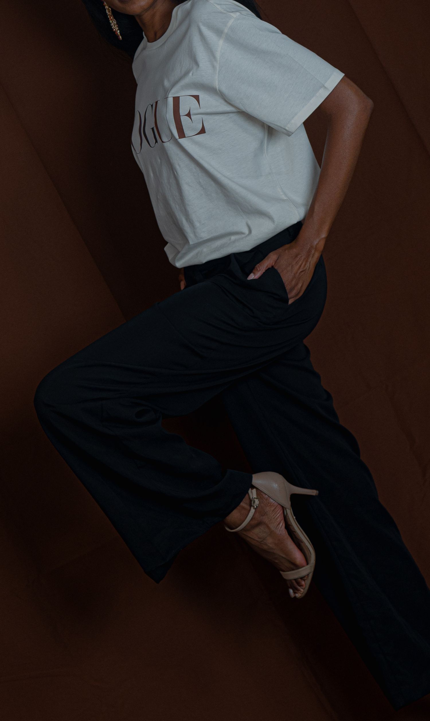 A cropped fashion photo showing white Vogue t-shirt and dark denim in dramatic lighting.