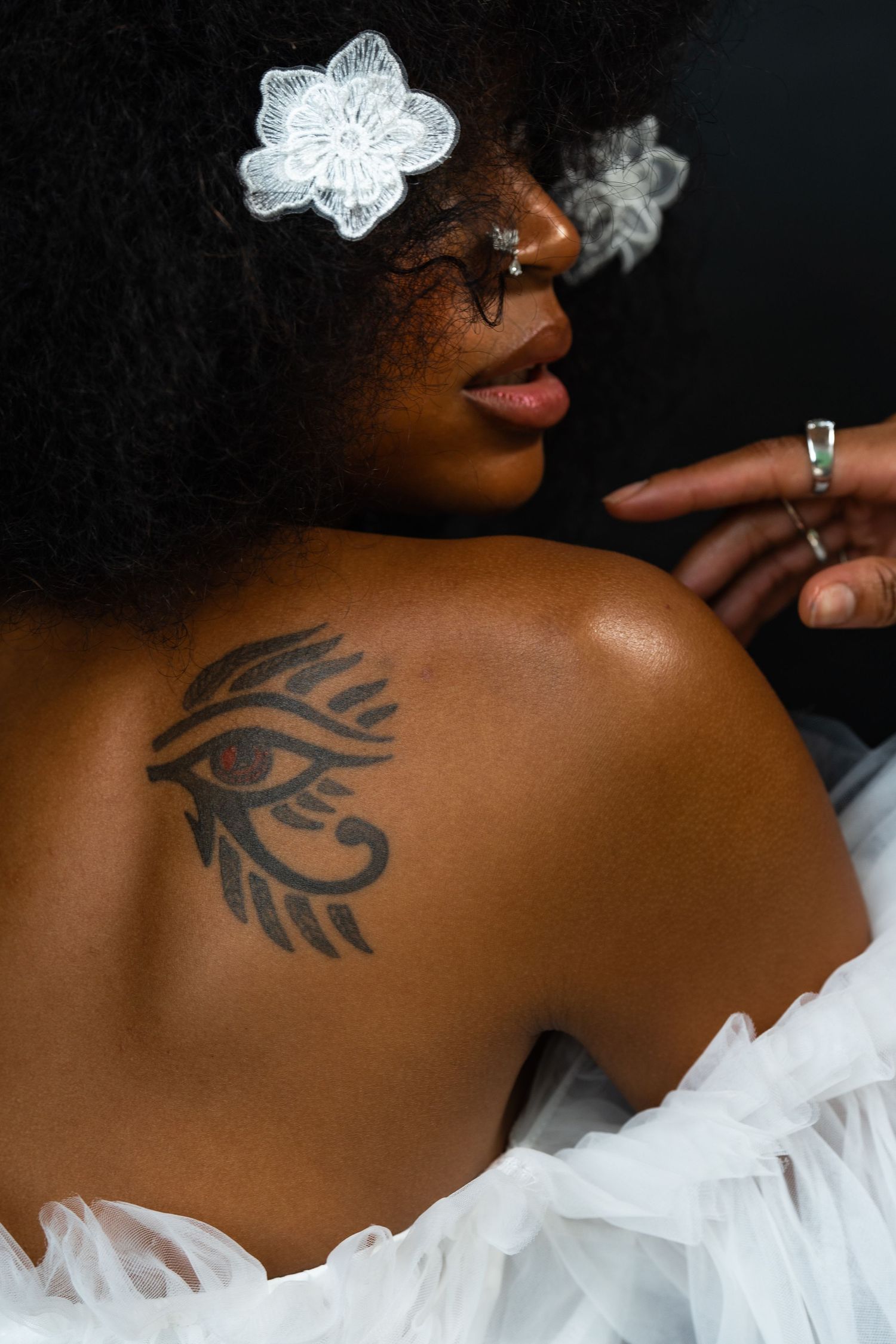 Close-up profile highlighting shoulder tattoo and natural hair adorned with crystal butterfly accessories.