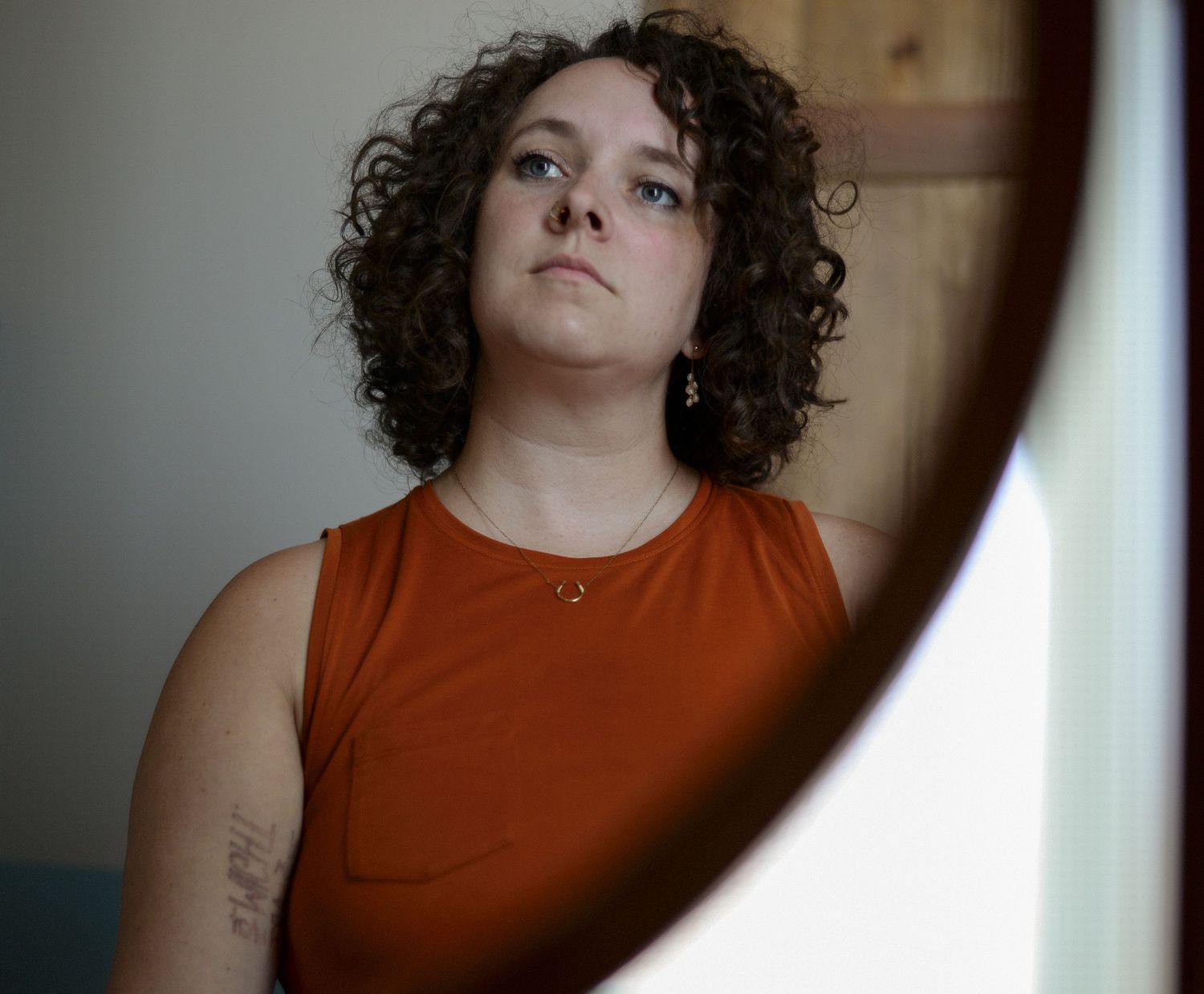 Self portrait of the photographer, Kate Gilmore, in a mirror of a natural light soaked room with earthy decor.