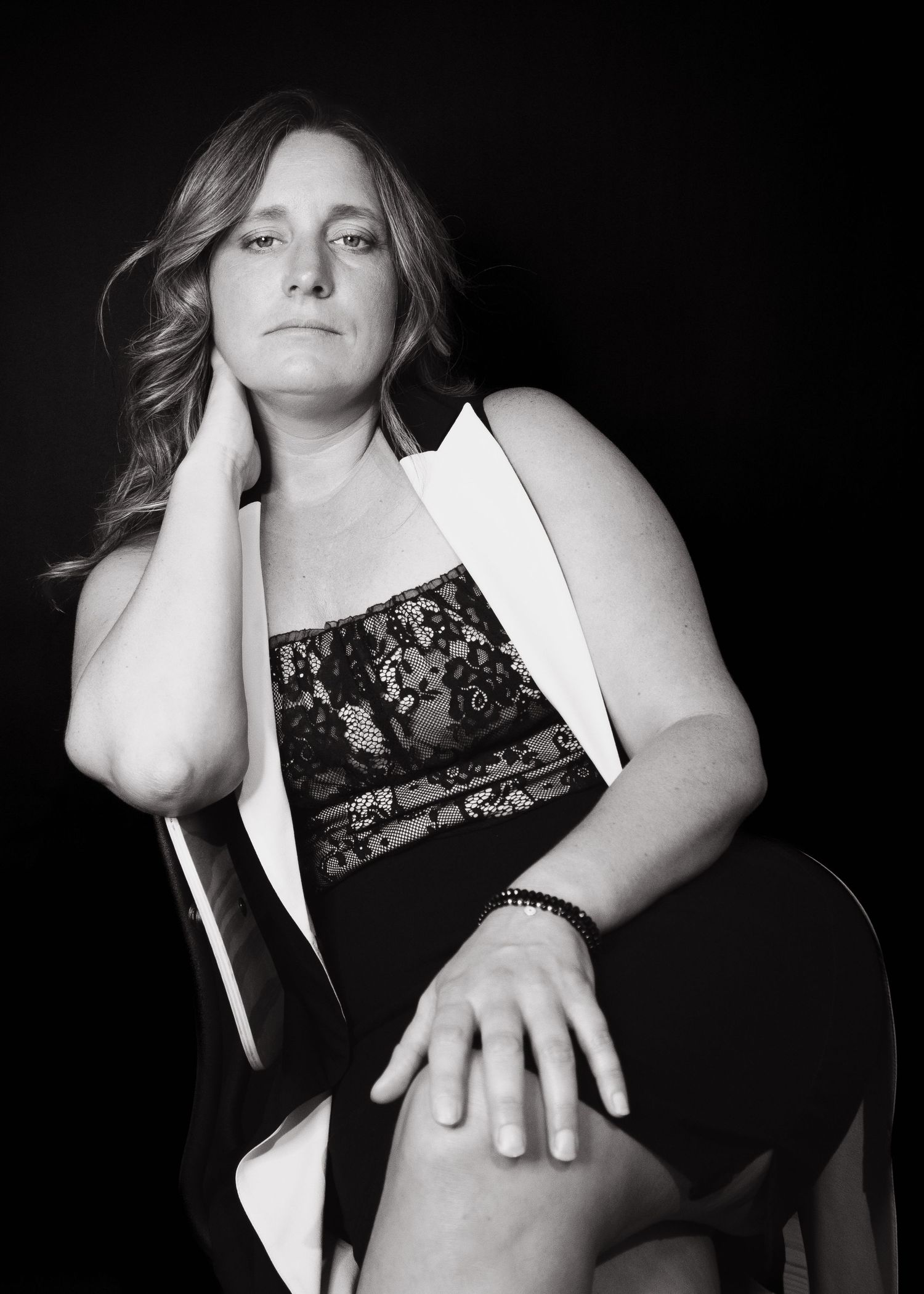 Black and white portrait of woman in her 40s with a serious gaze and strong posture, creating a timeless mood.
