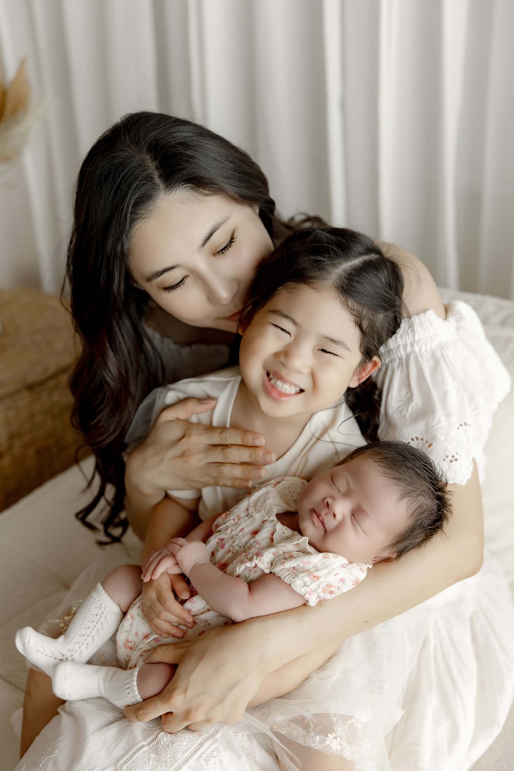 A tender family moment showing three generations sharing loving embraces while sitting together in white attire.