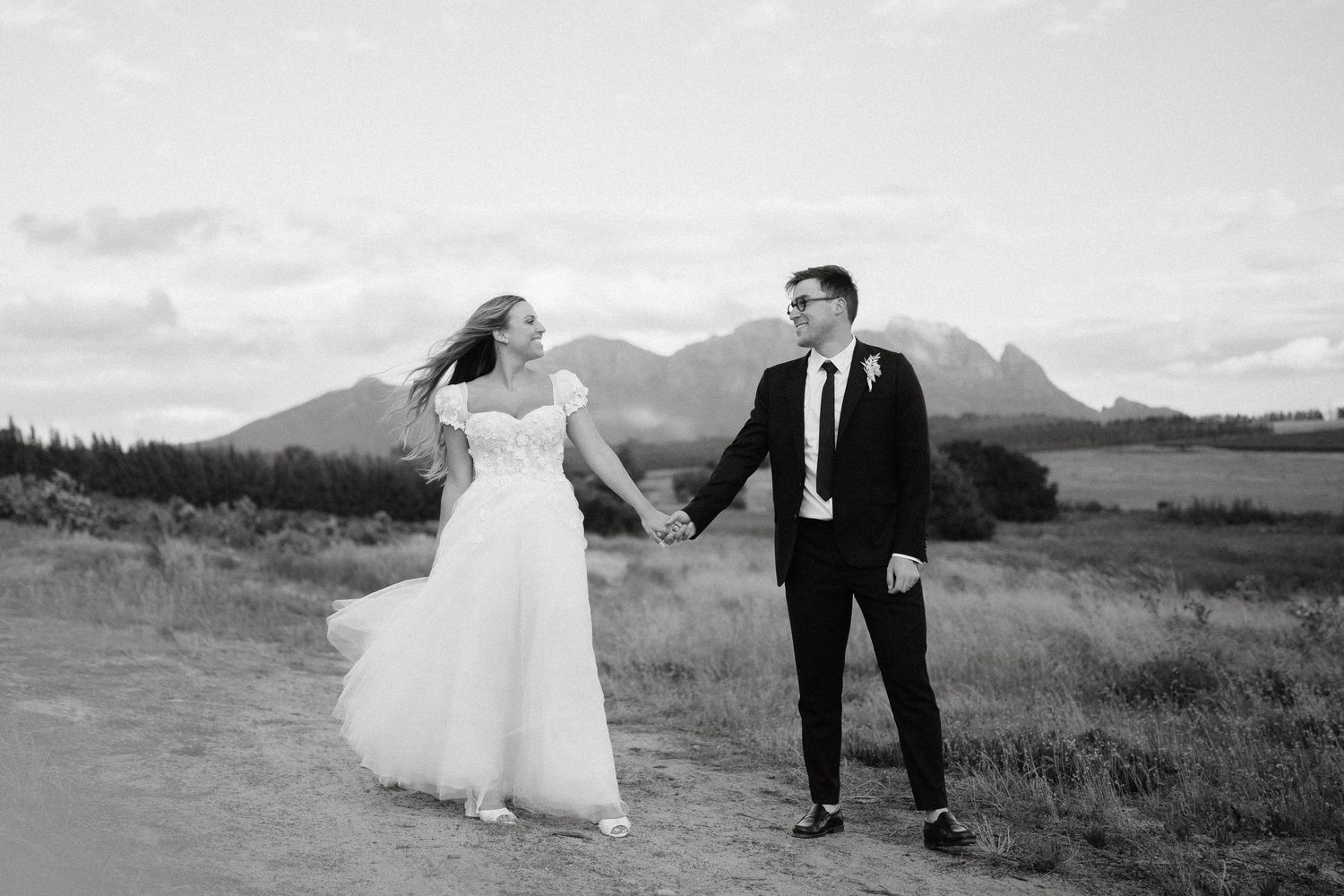 A dramatic wedding photo with flowing dress movement against a mountain backdrop.