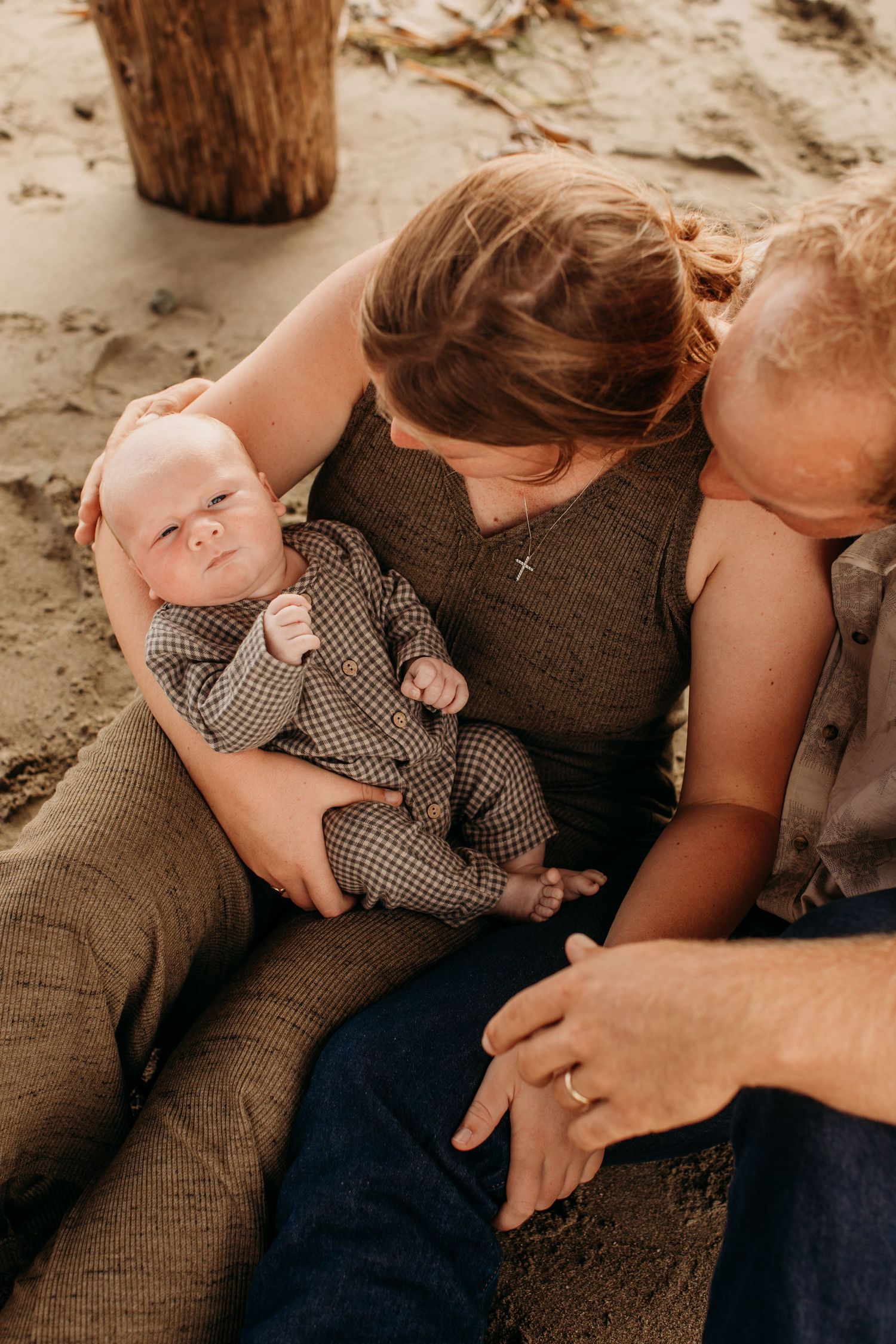 Tender family moment captured on sandy beach in warm lighting.