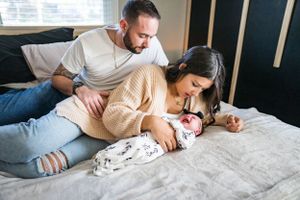 Parents cuddling with their newborn baby on a cozy bed.