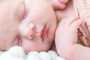 A sleeping baby lies peacefully on soft bedding with a gentle, serene expression.