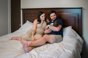 Intimate family moment with newborn baby on a bed.