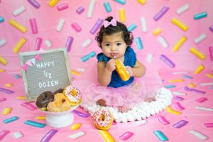 Colorful donut-themed half birthday photo shoot with sprinkle backdrop.