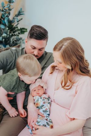 A loving family moment as they gather together to admire their newborn baby wrapped in a floral swaddle.