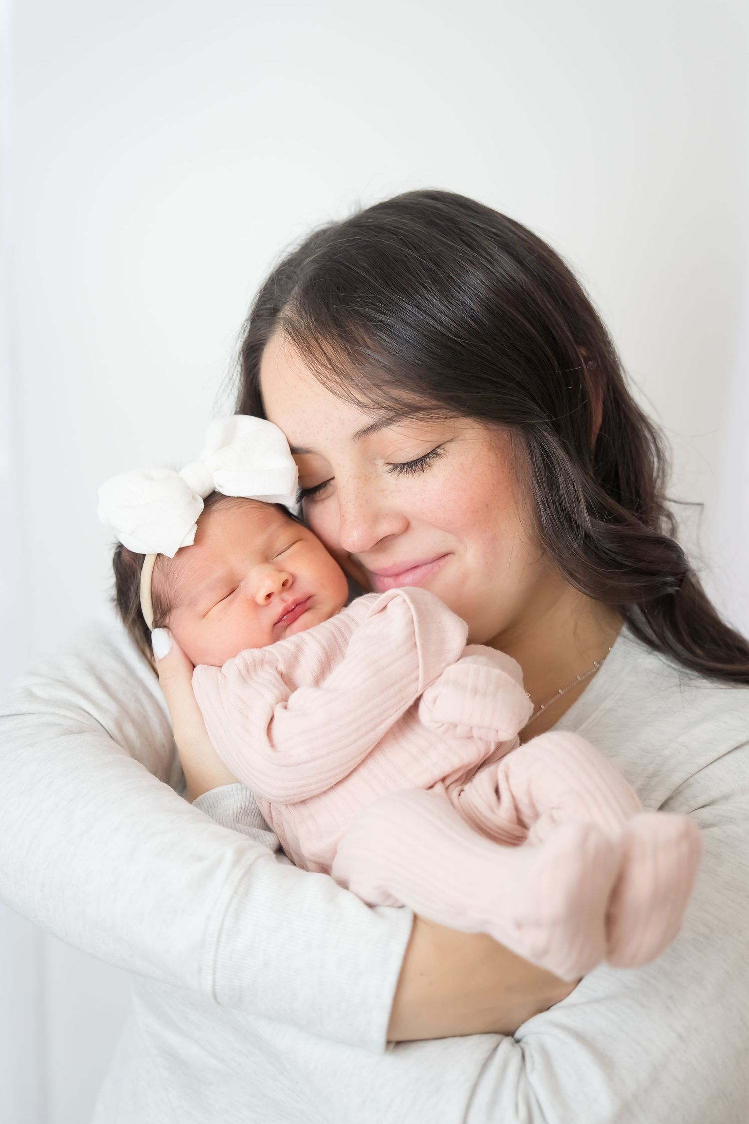 A tender moment captured showing a mother and baby sleeping peacefully together in soft white bedding.