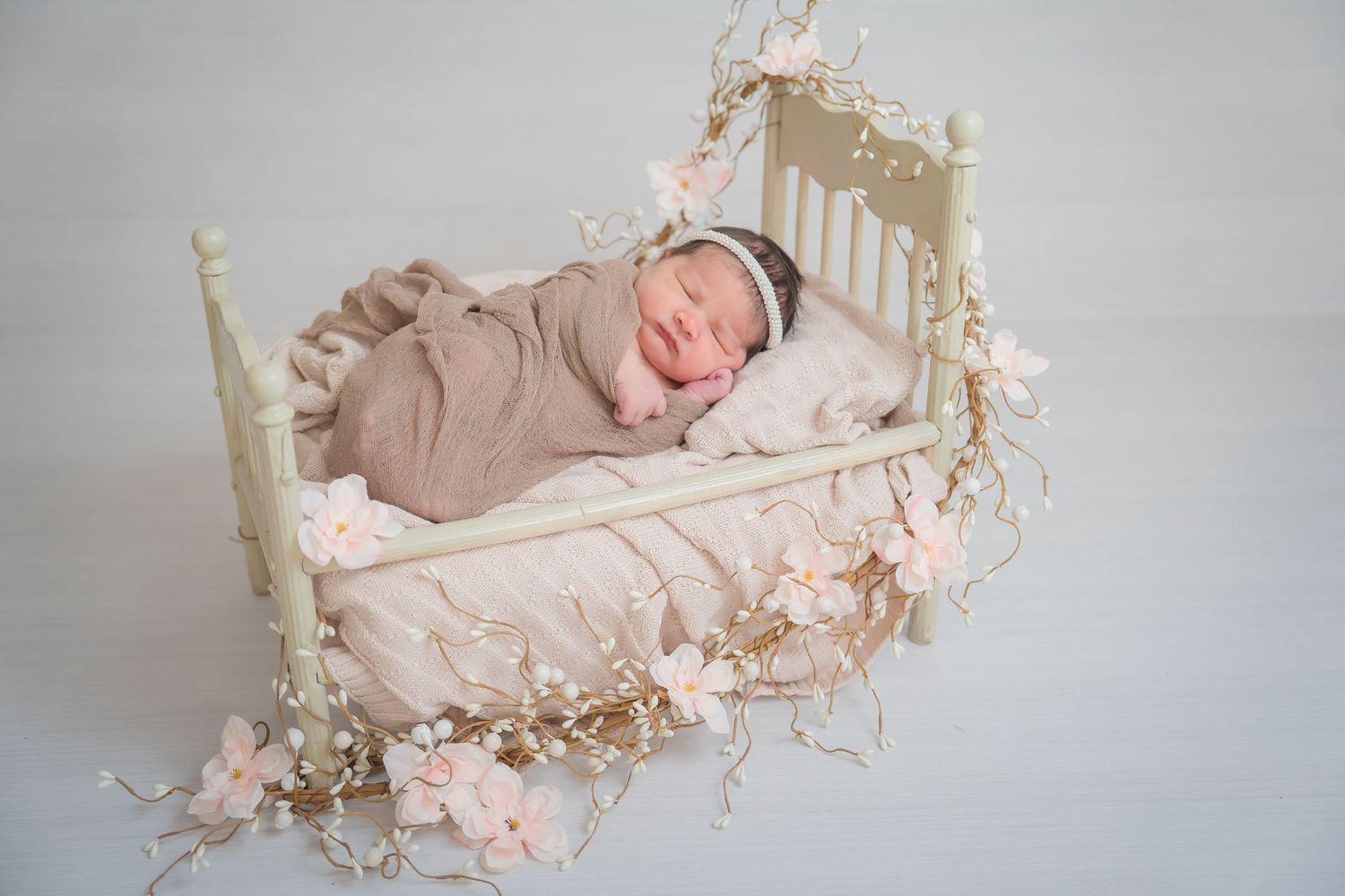 Series of peaceful sleeping newborn photos with soft pink and beige tones in minimalist studio setting.