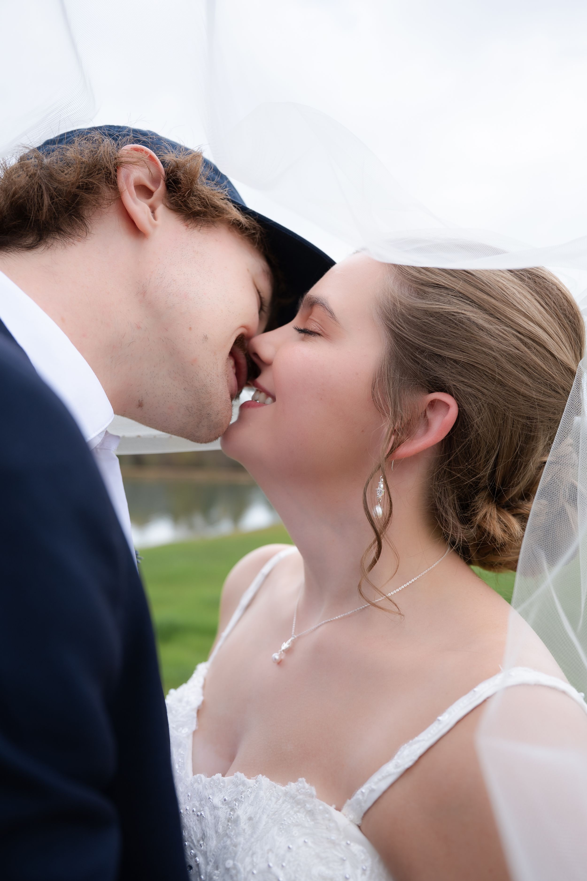 Candid wedding photography captures joyful laughter between newlyweds outdoors.