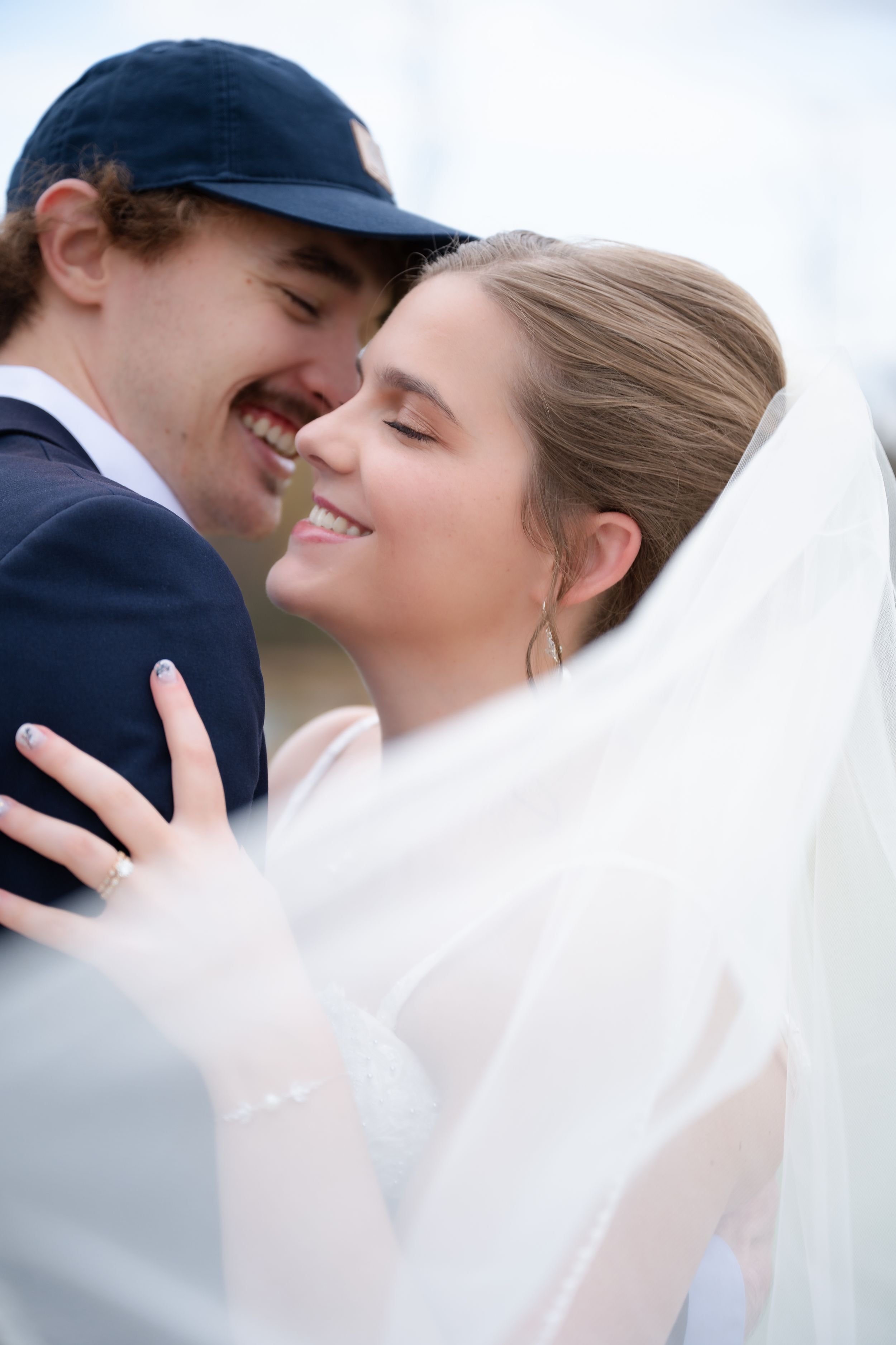 A romantic wedding moment captured in a series of four close-up shots showing the couple embracing under a white veil.