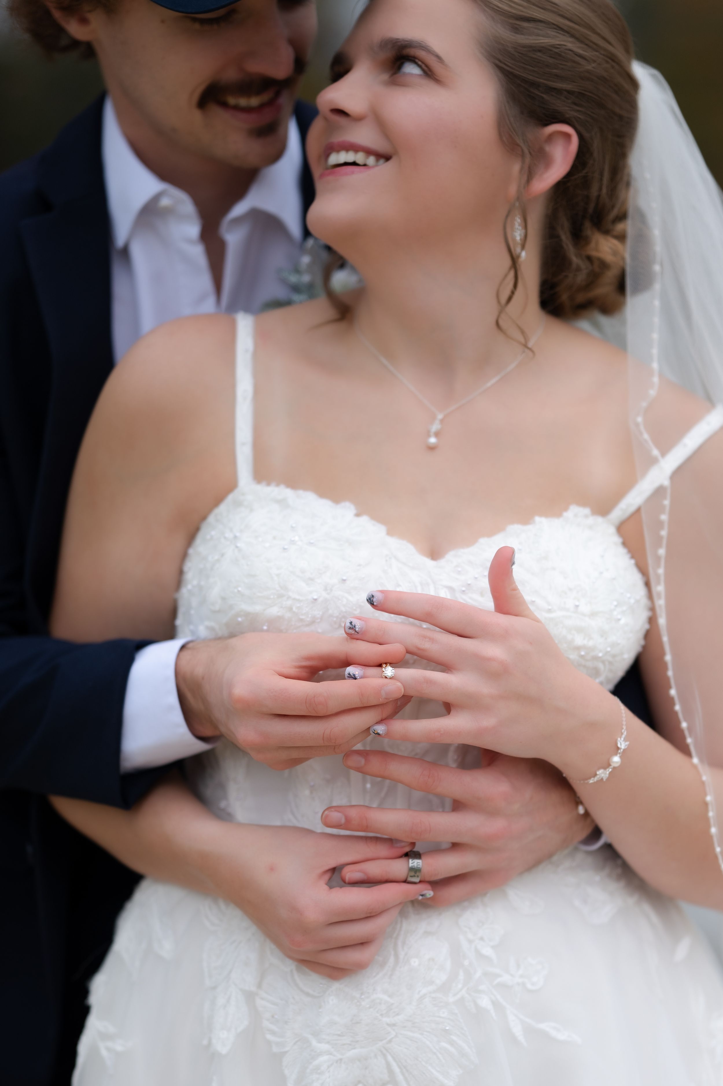 A couple shares tender moments in wedding attire as they display their rings.