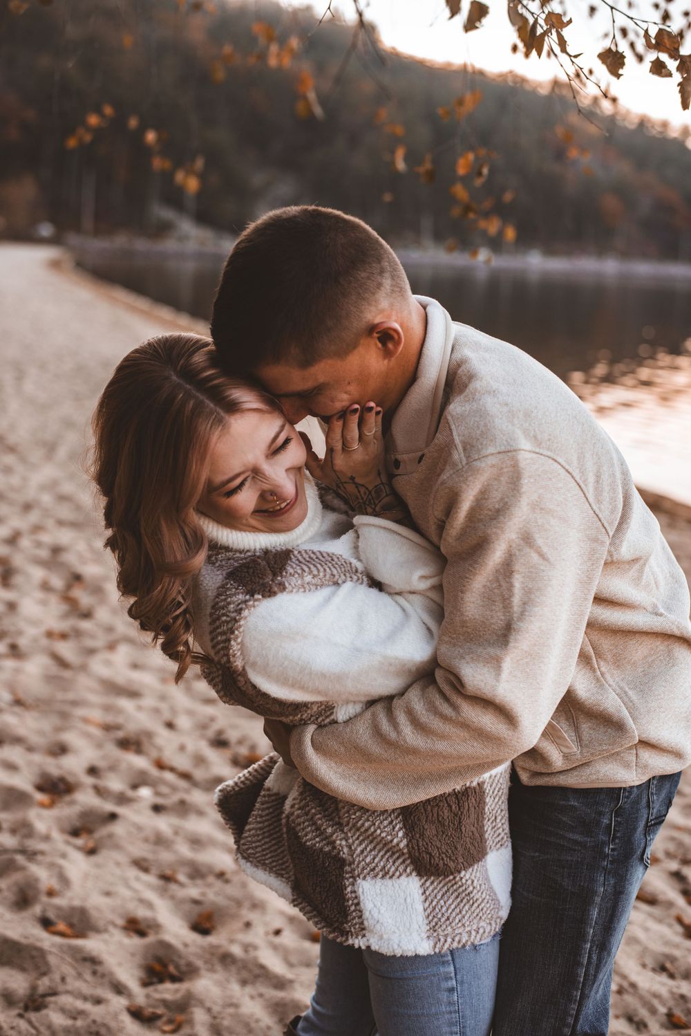 Couple in matching sweaters sharing playful moment on autumn beach.