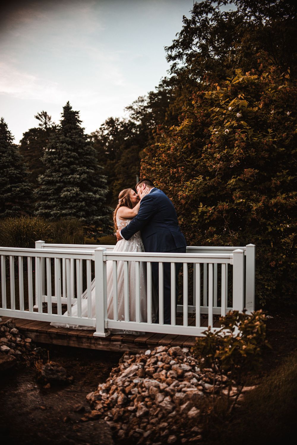 Romantic sunset moment on white bridge railing surrounded by autumn trees.