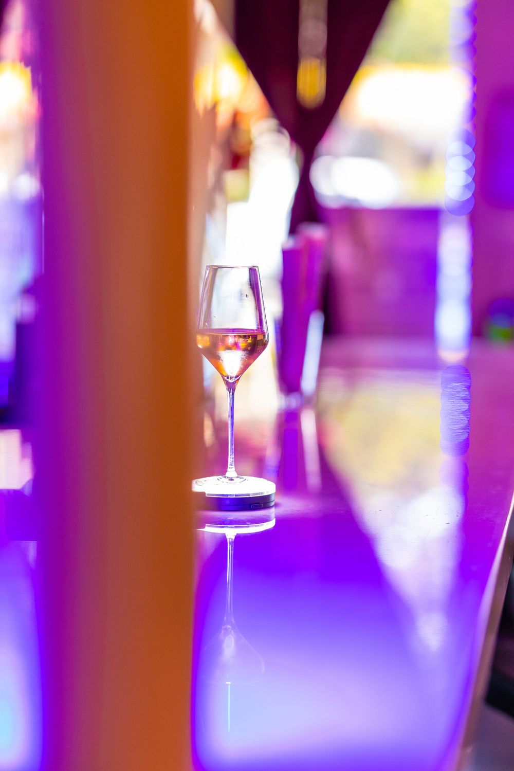 Wine glasses with colorful purple ambient lighting create an elegant nightclub or bar atmosphere.