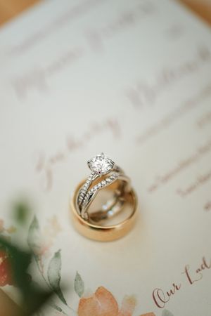 Close-up view of an elegant diamond engagement ring and wedding band set on a textured white surface.