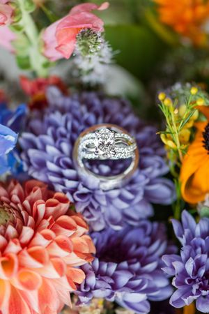 Elegant diamond engagement ring nestled among colorful coral and purple flowers with delicate petals.