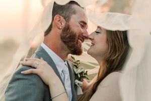 A romantic couple shares tender moments in wedding attire against a soft blurred background.