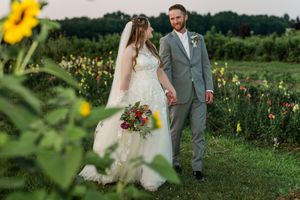A couple walks through a vibrant wildflower field during a rustic outdoor wedding celebration.