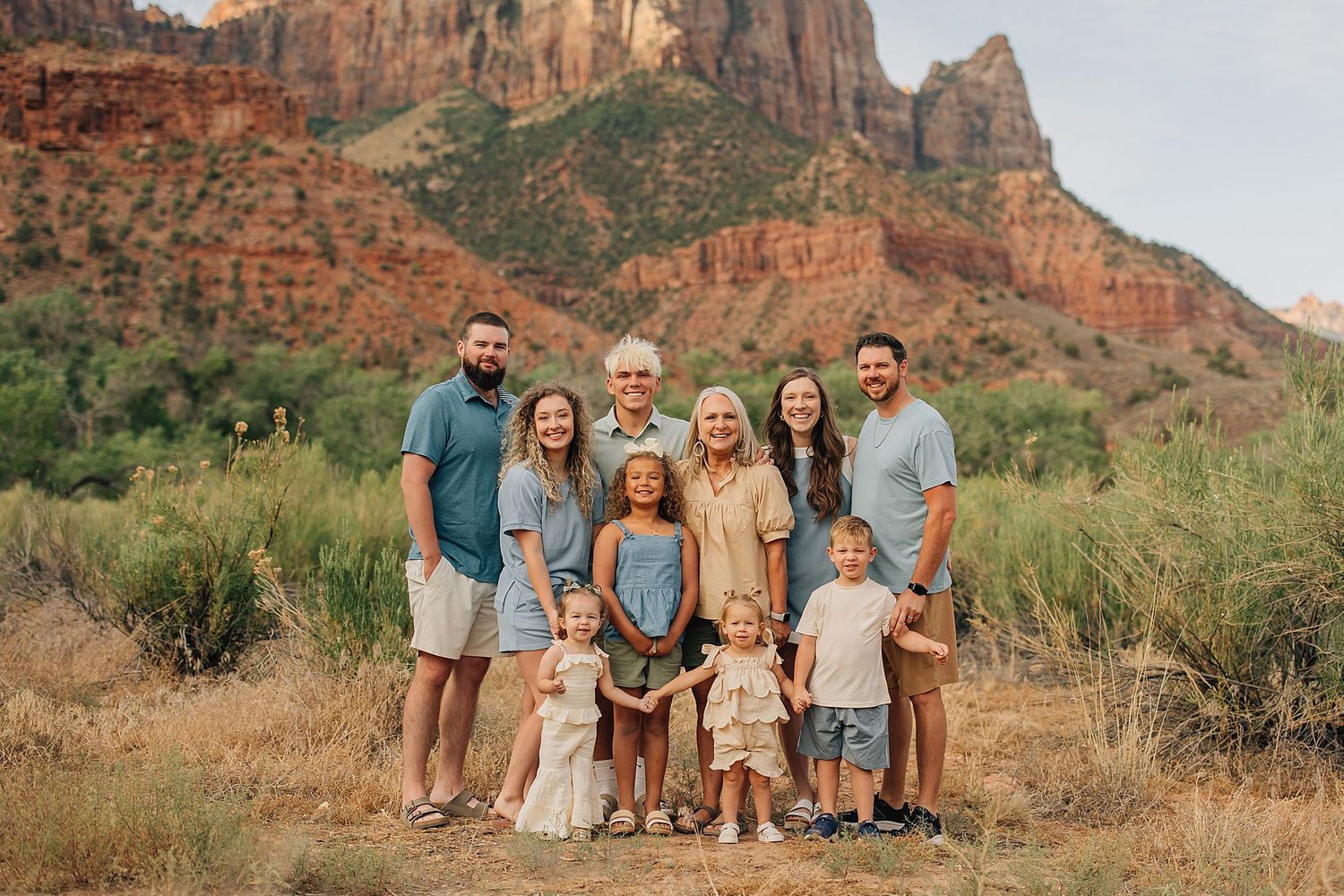 Large family posing together in front of red rock canyon landscape at Zion National Park.