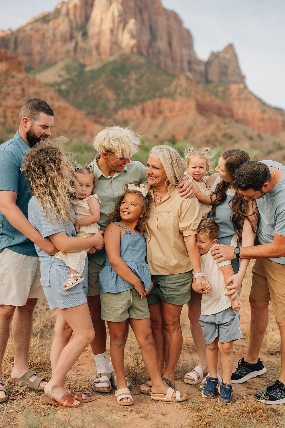 Multi-generational family poses together outdoors with stunning red rock Zion National Park mountains in the background.