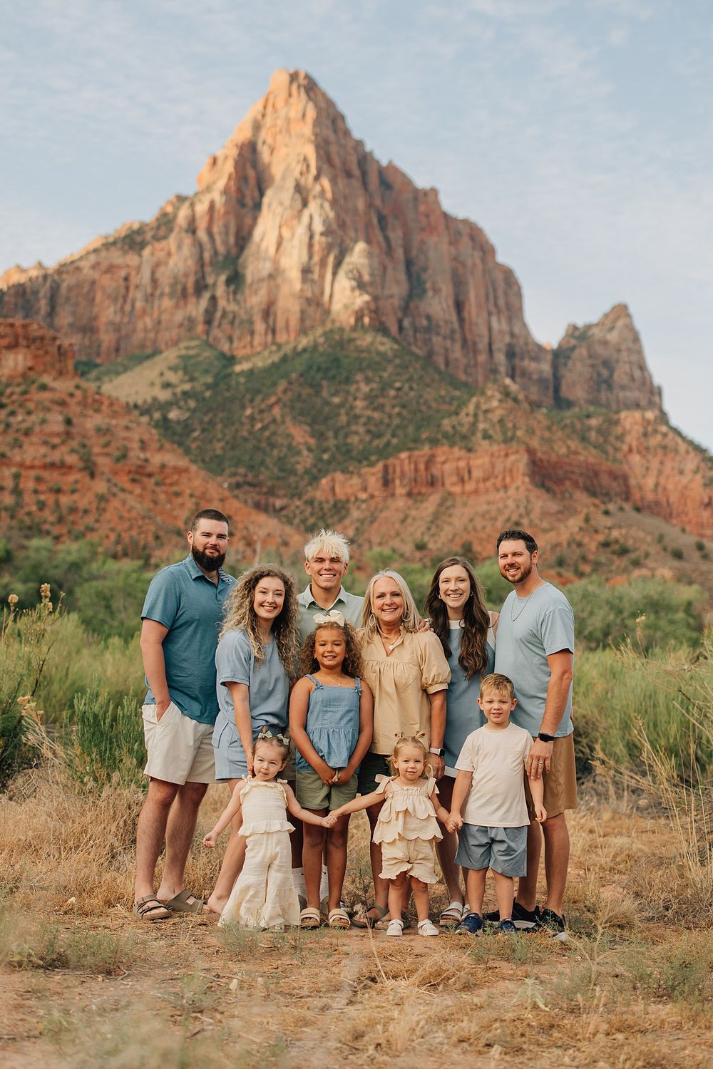 Multi-generational family portrait with red rock mountains at Zion National Park during golden hour.