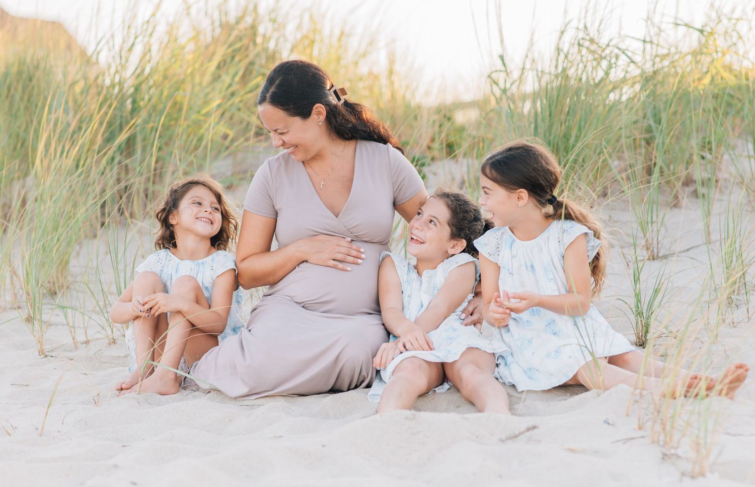Candid family portrait at Monmouth Beach NJ at sunset with mother and children wearing light blue and white linen clothing.