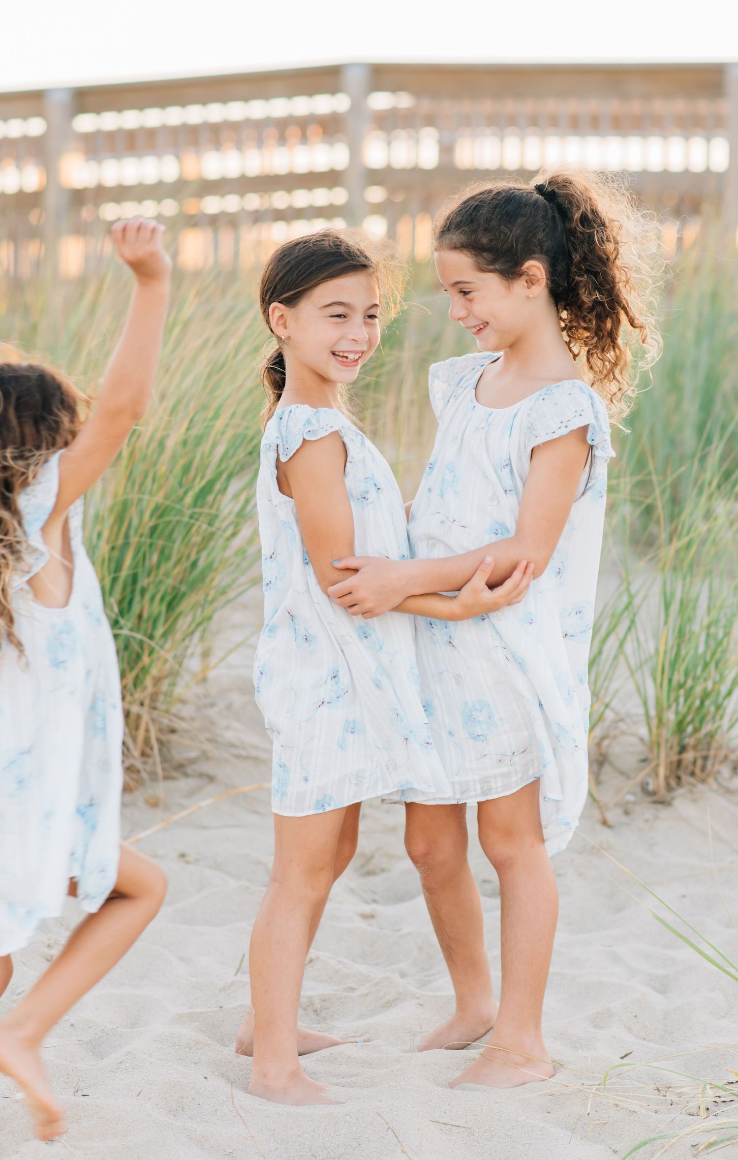 Two young siblings laughing and hugging on the shoreline during a sunset family photo shoot in Monmouth Beach, NJ.